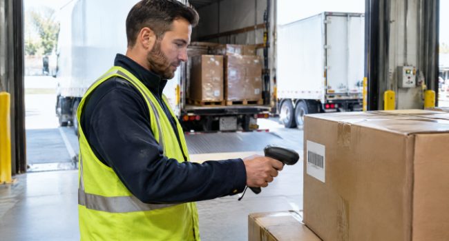 Worker scanning a carton barcode label at the loading dock to prevent retail chargebacks