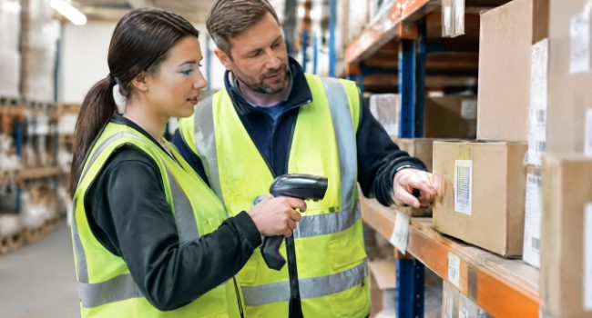 Trainer showing a temporary warehouse worker how to use a barcode scanner