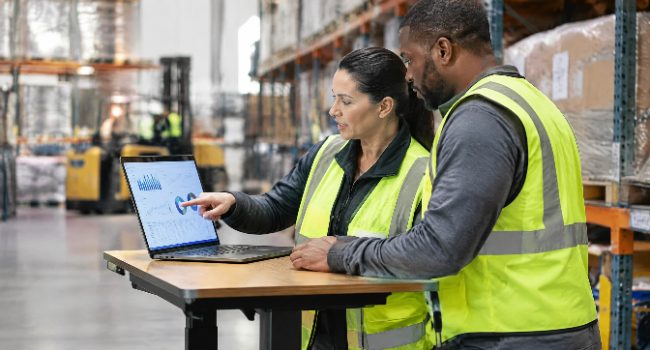 Warehouse managers reviewing labor and productivity data on a laptop