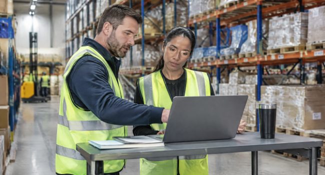 Warehouse operations planners reviewing a multi-site rollout plan on a laptop
